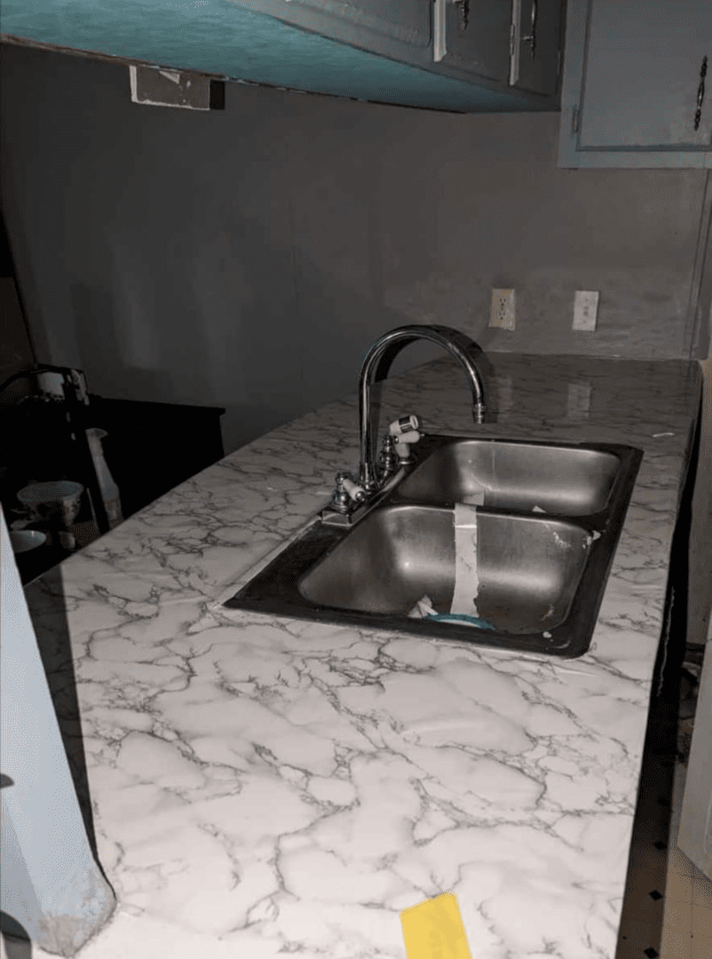 Double kitchen sink with faucet and marble countertop.