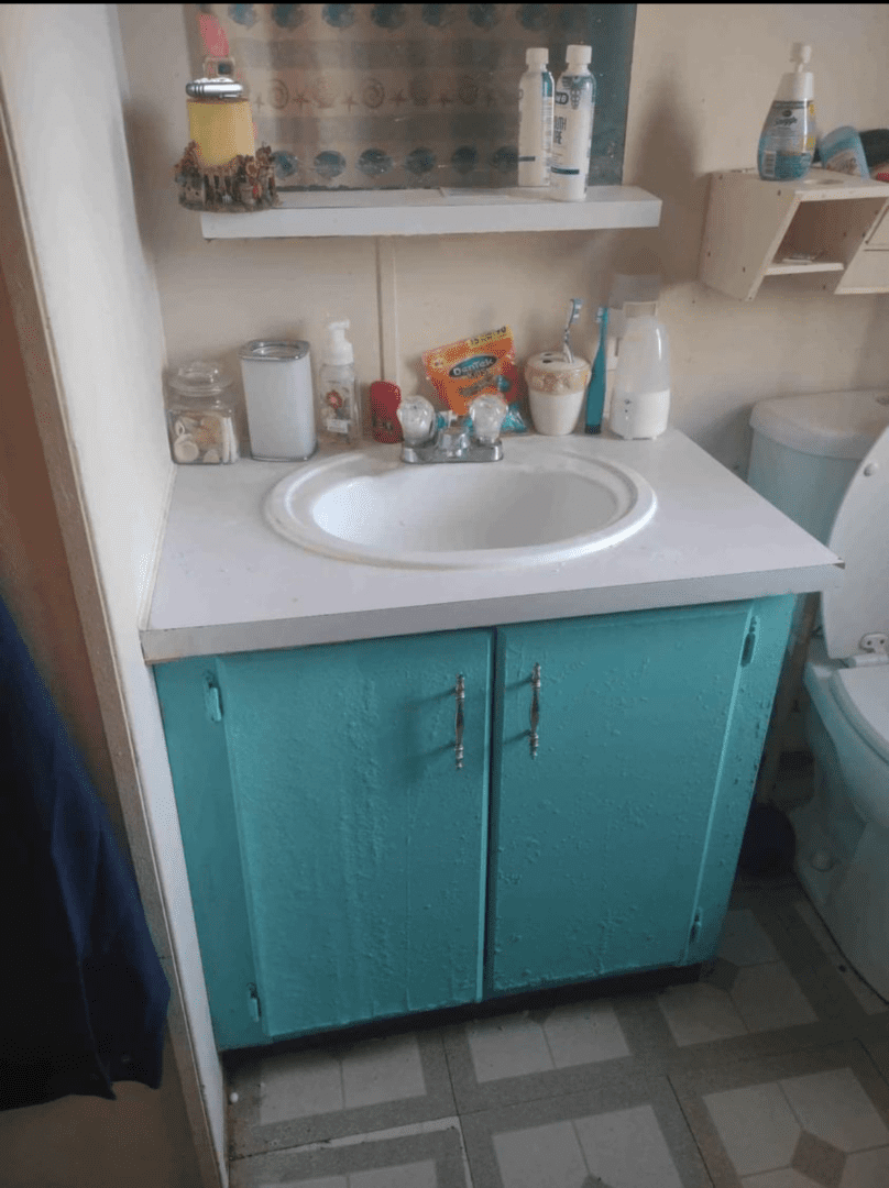 Teal bathroom cabinet with white sink.