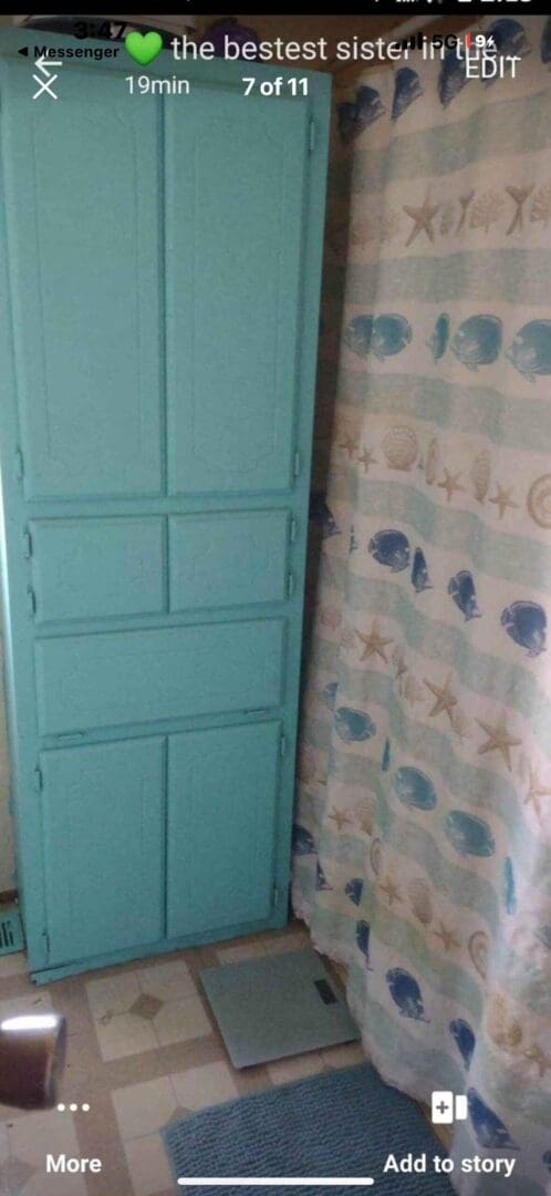 A teal cabinet with a bathroom scale in front.