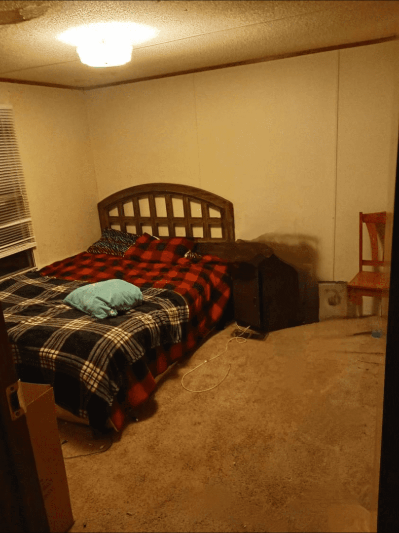 Bedroom with plaid bed and a chair.
