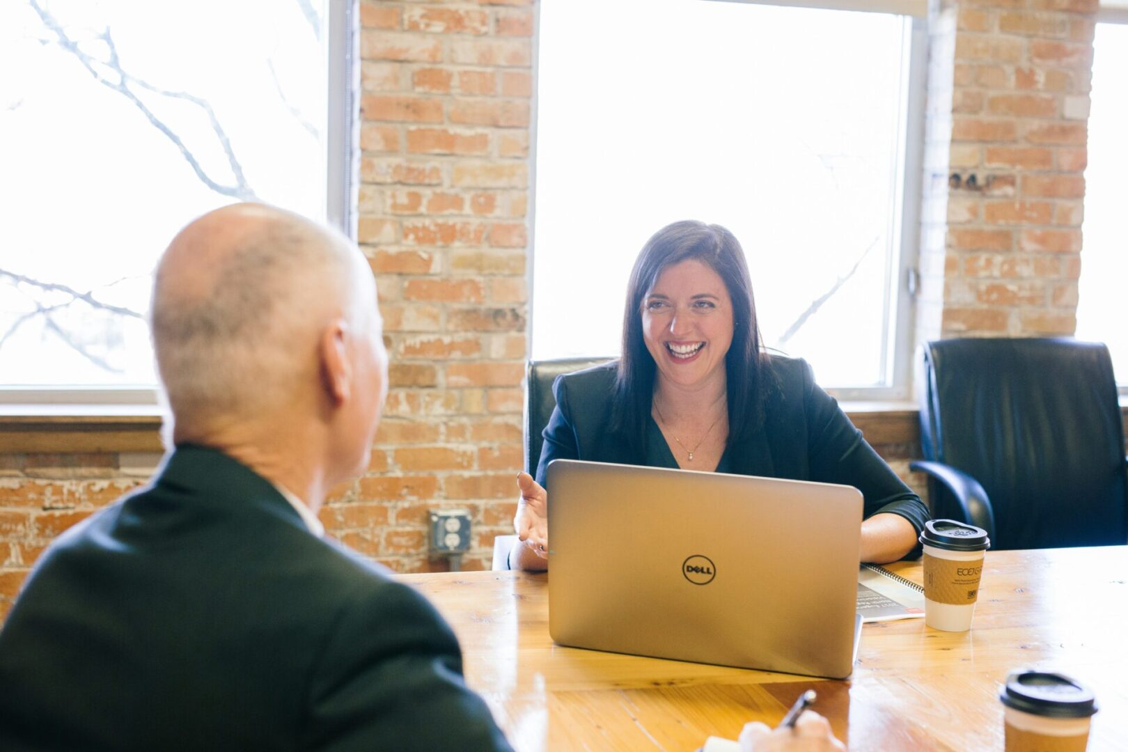 Businesswoman smiling at colleague with laptop.