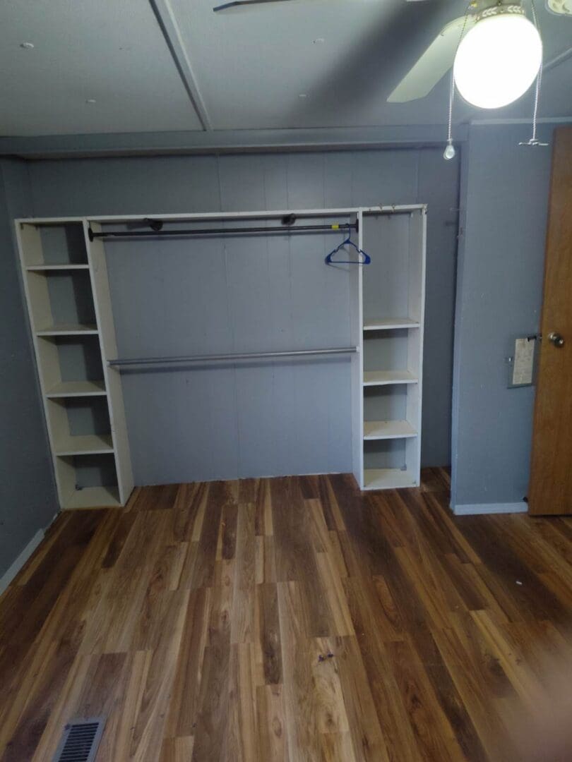 Empty room with wood floor and shelves.