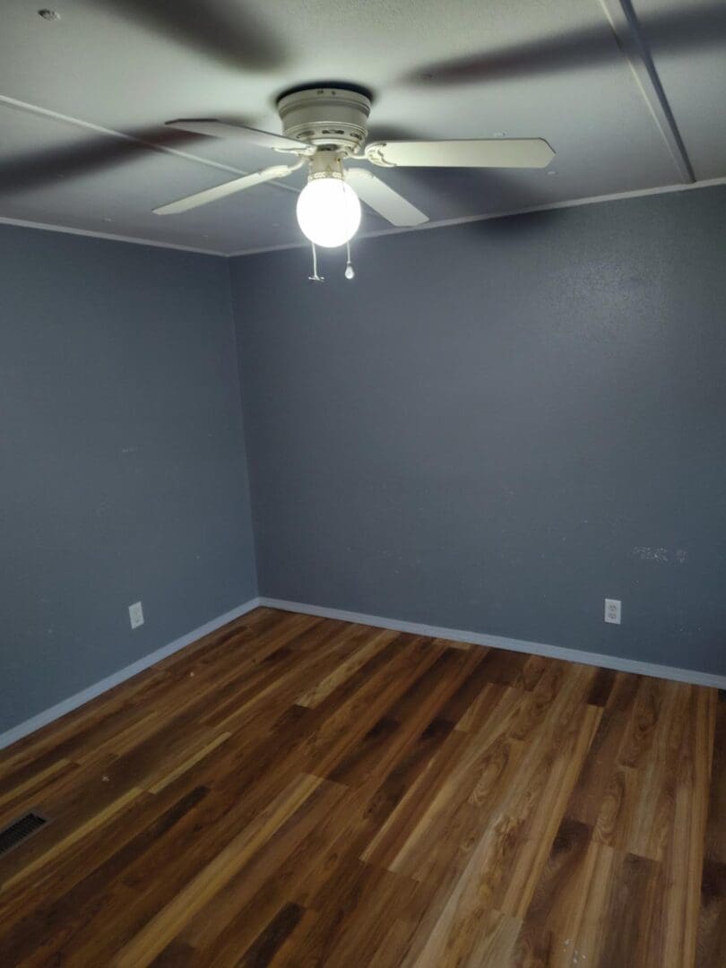 Empty room with wood floor and ceiling fan.