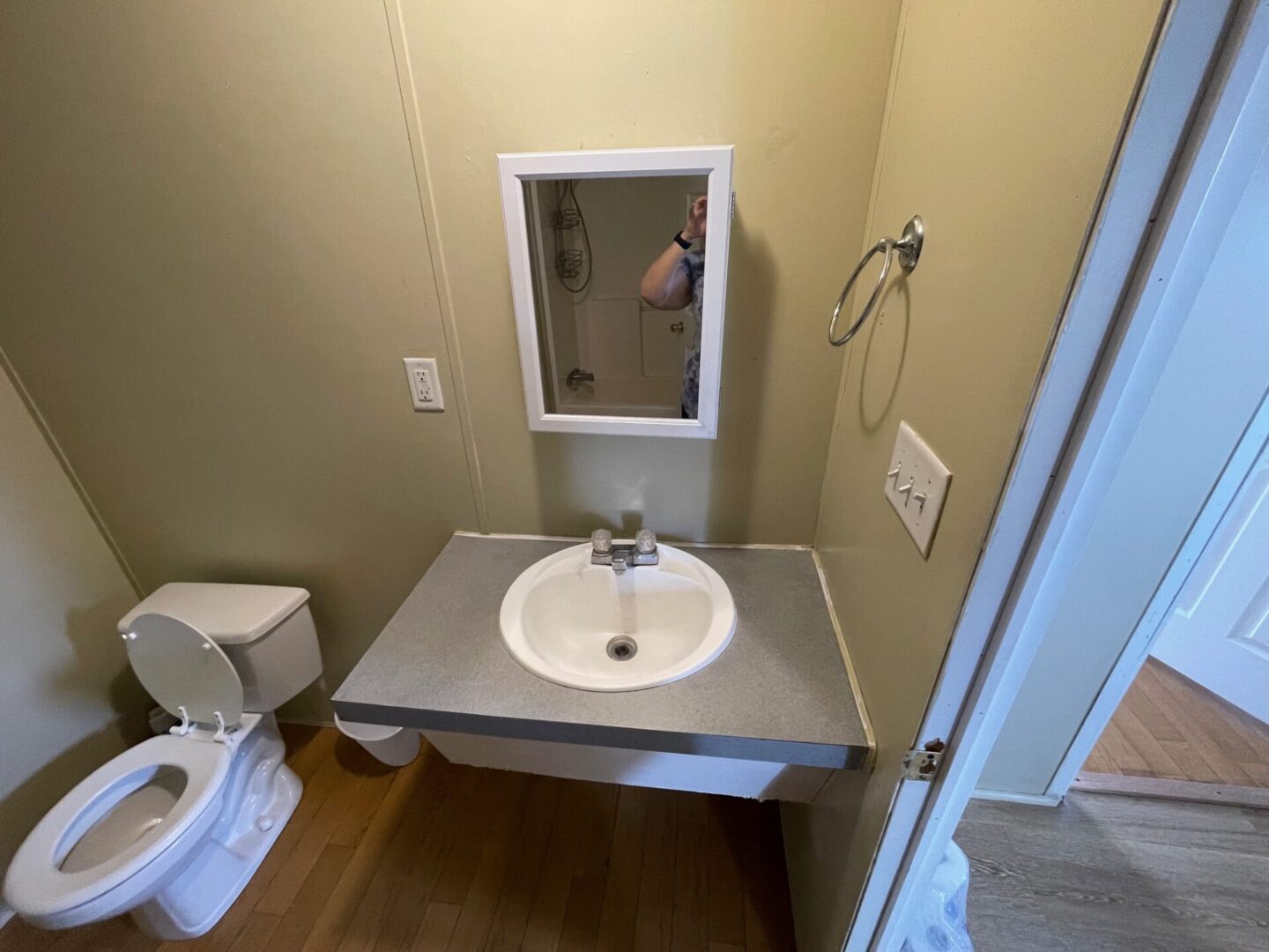 Bathroom with toilet, sink, and mirror.
