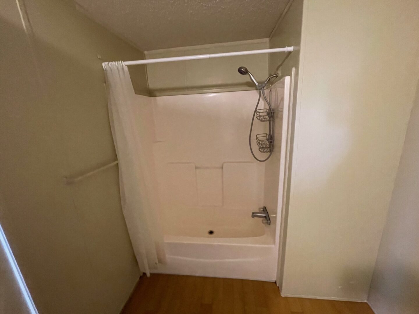 White shower with shower curtain and tile floor.