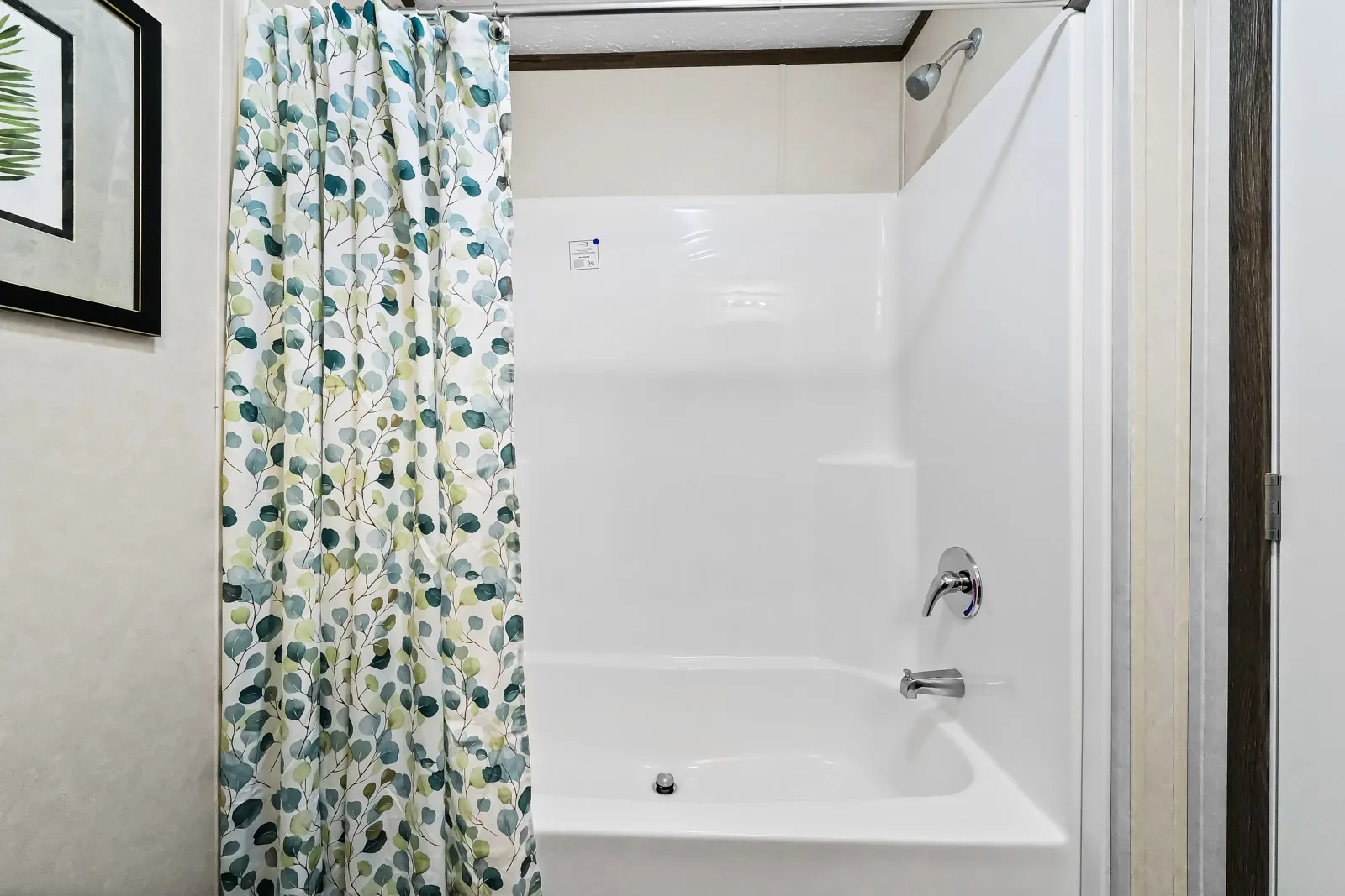 White tub with green leaf shower curtain.